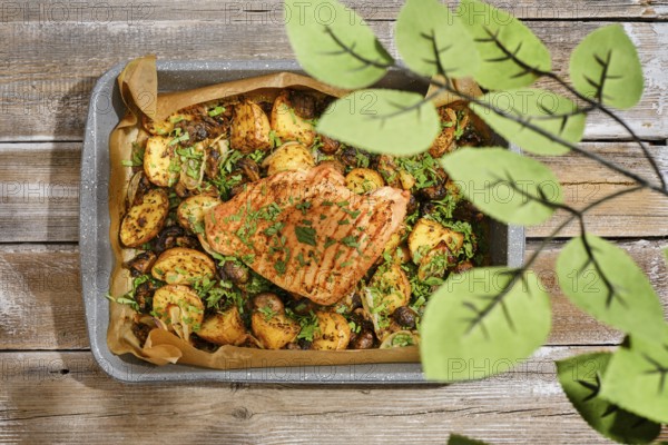 A roasted turkey breast is presented in a baking tray alongside golden potatoes and herbs. The