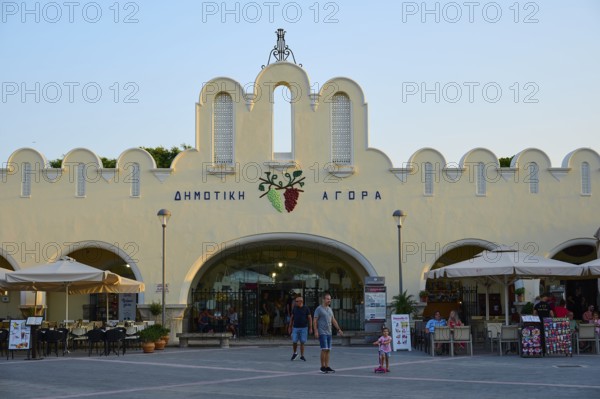 Agora, Municipal market hall, Lively market with white buildings and parasols in the foreground,
