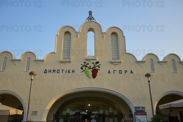 Agora, Municipal Market Hall, White market hall with Greek writing and grape emblem, illuminated by