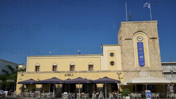 Cinema, Eleftherias Square, Historic building with clock tower and cafés under a blue sky, Kos