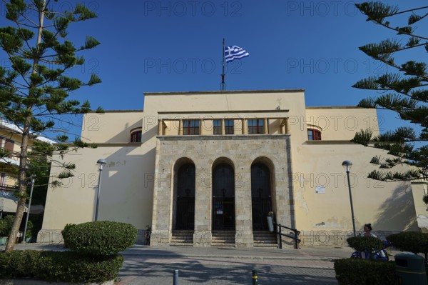 Archaeological Museum, beige building with Greek flag on the roof, symmetrical architecture,