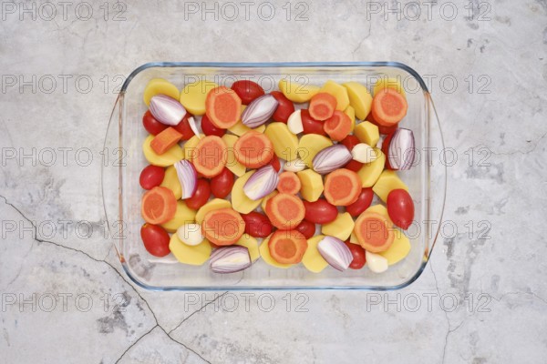 Fresh colourful vegetables like carrots, tomatoes, potatoes, onion and garlic cloves all neatly
