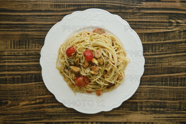 A generous serving of spaghetti topped with an assortment of seafood, including shrimp and mussels,
