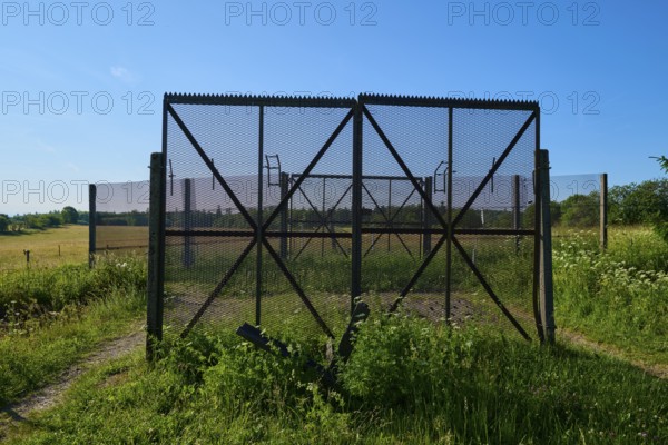 Border fence of the former inner-German border, surrounded by green meadows under a clear blue sky,