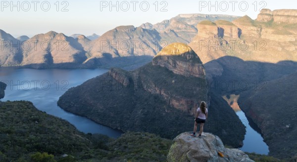Hiker enjoying panorama, sunset at Blyde River Canyon with Three Rondawels peak, view of canyon