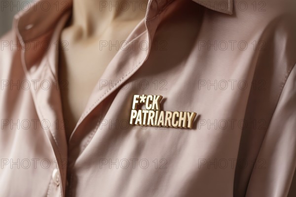 Gold pin reading FCK patriarchy on pink blouse. Bold feminist statement against gender inequality