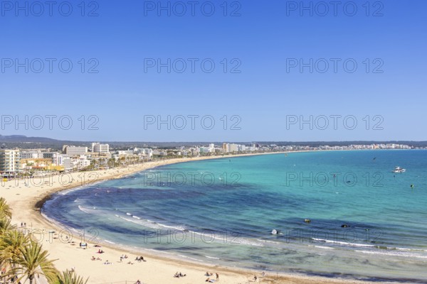 Aerial view at a tourist resort area with sunbathing people on the sand beach by the blue