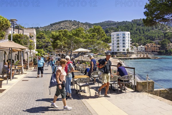 Tourists on a boardwalk and restaurants by the Mediterranean Sea at a tourist resort a sunny summer