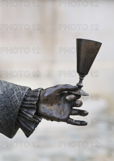 Close-up of hand holding champagne glass, statue of Louis XV in front of Hotel Champagne De Venoge,