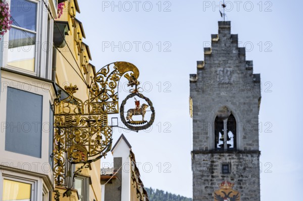 Artistic golden hanging sign, nose sign, old town centre, behind Zwölferturm, Sterzing, South