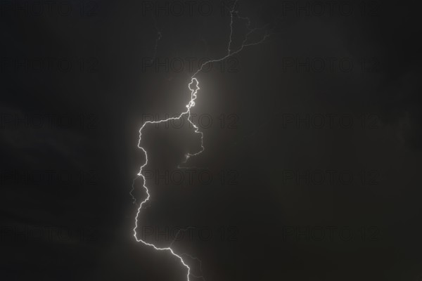 Dark clouds gather as lightning strikes light up the night. The intense storm brings thunder and