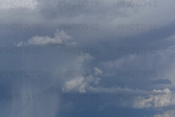 Dark storm clouds gather in the sky over a vast rural landscape, signalling an impending summer