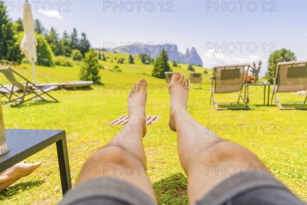 Person lying in a deckchair enjoying the summer landscape and the peace and quiet in a meadow, Alpe
