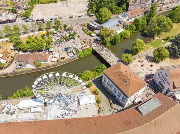 View from above of a summer festival with Ferris wheel, bridge and many people along a river in the