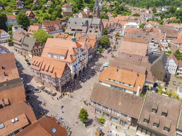 Aerial view of a colourful half-timbered town with a lively market square and church on a summer's