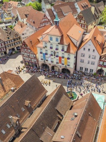 Crowd of people in front of historical buildings at a town festival, decorated with colourful
