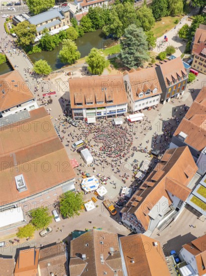 Aerial view shows a dense cityscape with people on a square, surrounded by buildings and trees, 950