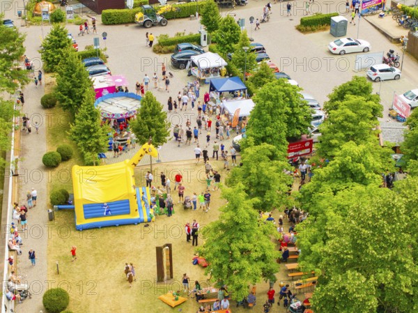Park full of people and children's attractions with colourful tents under green trees, 950 years of