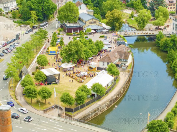 Aerial view of a small park with people, surrounded by a river and city infrastructure, 950 years