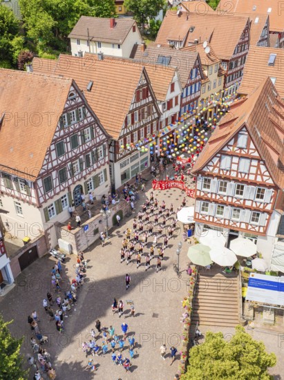 A large crowd gathers in front of half-timbered buildings during a colourful parade, 950 years of