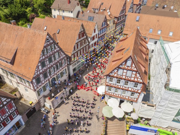 From above you can see people in formation and colourful balloons next to historic house facades,