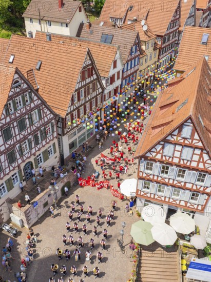 A colourful event with lots of balloons and people between historic half-timbered houses, 950 years