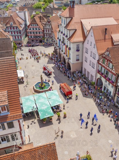 Viewed from above, a parade passes half-timbered houses around a central fountain, 950 years of