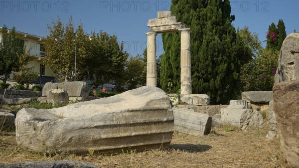 Debris of a fallen column lying on dry ground in front of a stone archway, Ancient Agora, Kos Town,