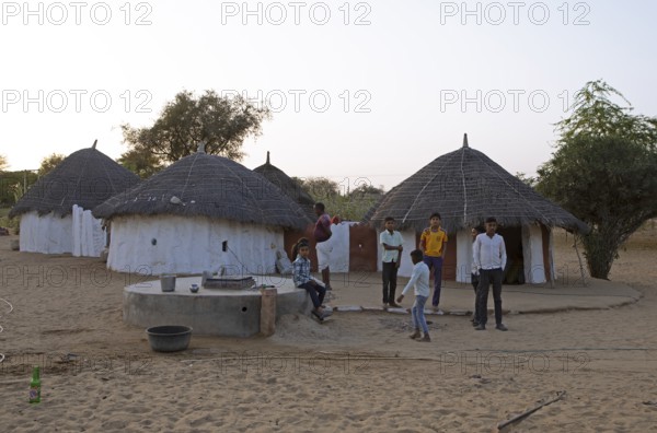 Indian desert dwellers, behind typical circular buildings in the Thar Desert or Great Indian