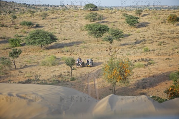 Jeeps waiting under a dune in the Thar Desert or Great Indian Desert, near Jaisalmer, Rajasthan,