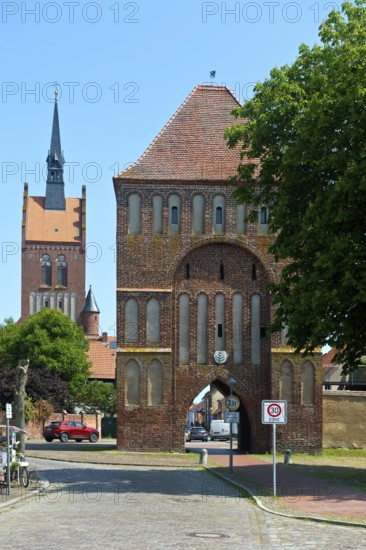 Brick building Anklamer Tor, St Mary's Protestant Church at the back, town of Usedom, island of