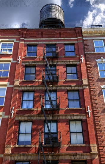 Residential building with fire escapes and wooden water tank on the roof, Downtown NY, New York