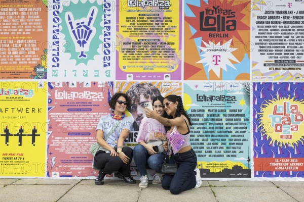 Festival visitors taking photos of themselves in front of Lollapalooza Festival posters from