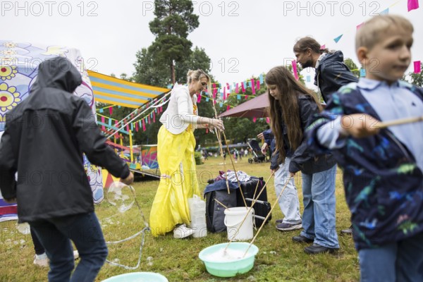 An artist makes soap bubbles with children at Kidzapalooza at the Lollapalooza Festival in the