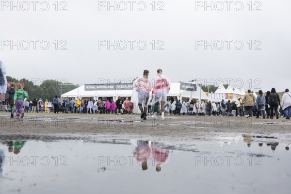 Festival-goers reflected in a puddle at the Lollapalooza Festival in the Olympic Stadium and on the
