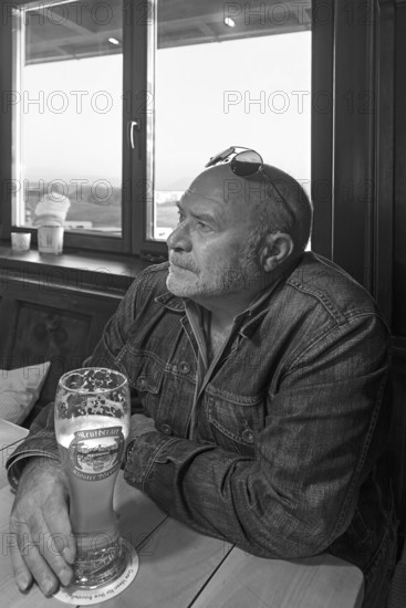 Elderly gentleman with sunglasses and wheat beer in a pub, black and white, Bavaria, Germany