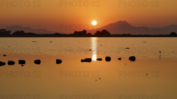 Tranquil landscape with sunset over a lake and distant mountains, salt lake, Tigaki, nature