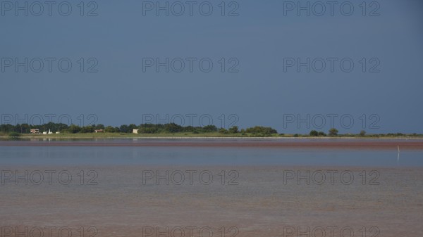 Tranquil coastal scene with blue sky and reflecting water, salt lake, Tigaki, nature reserve, hydro