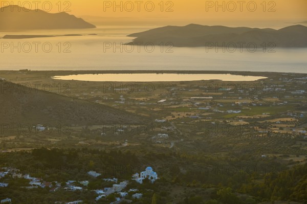 A view of a village and fields in front of the sea at sunset, salt lake, Tigaki, nature reserve,