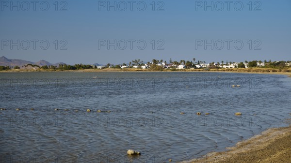 A coastal village on the shore of a lake in calm weather under a blue sky, salt lake, Tigaki,