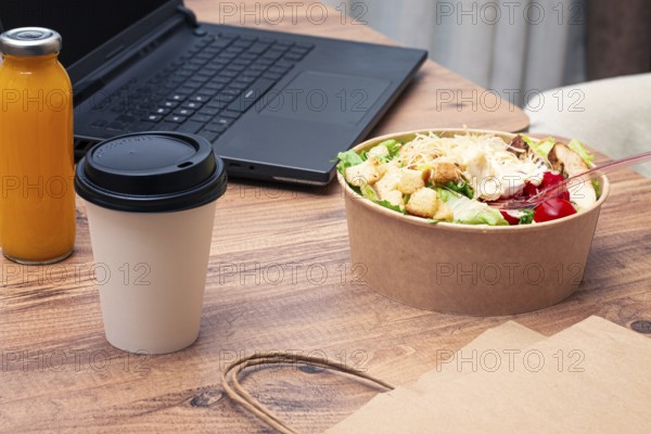 Work at home on a laptop, there is food on the table, salad, coffee and juice, delivery, there are