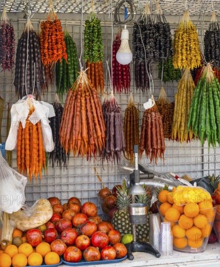 A market stall full of colorful fruits and traditional sweets with a juicer in the foreground,