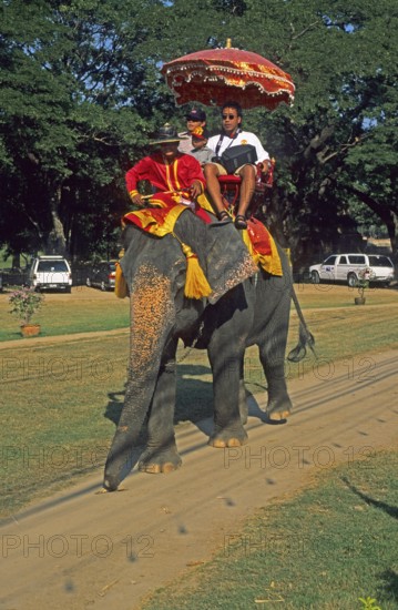 People, tourists, riding on an elephant through ancient sights, Ayutthaya, Thailand, December 2002,