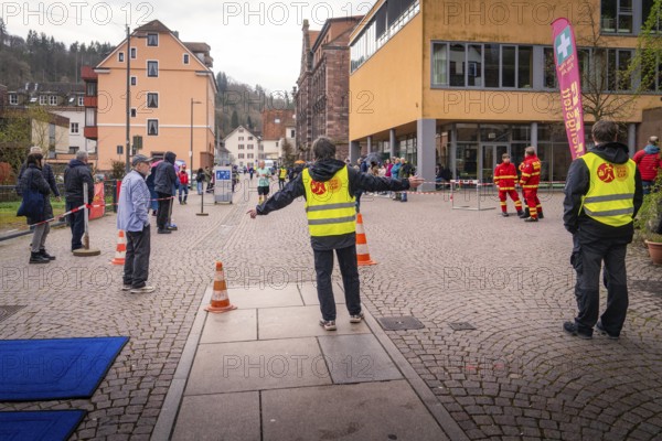 Group of people wearing safety vests at a roadblock in an urban environment, triathlon, Calw,