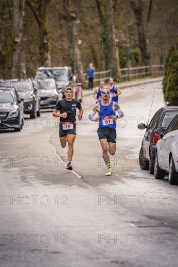 Two runners running on a road with parked cars and trees in the background, Triathlon, Calw,