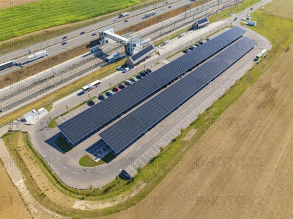 Solar system with parking spaces next to a well-traveled motorway and fields, e-charging park,