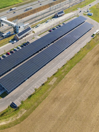 Solar system with adjacent parking spaces and parked cars under clear skies, e-charging park,
