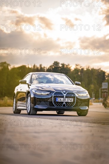 Black car on the road in natural setting at sunset, BMW i7 electric car, Deer E- Carsharing, Calw,