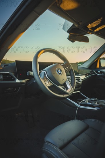 Modern car interior with stylish steering wheel and screens, in sunset light, BMW i7 electric car,