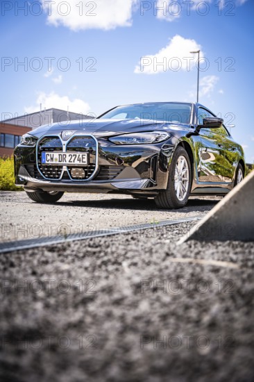 A black car is parked on a quiet road under a blue sky, BMW i7 electric car, Deer E- Carsharing,